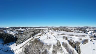 Saint George ski jump and ski slopes of Winterberg ski lift carousel photographed from the air. Panorama image of deserted winter sports area.