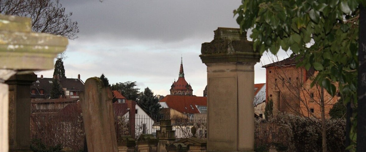 A cemetery with gravestones and a church with a red roof in the background.