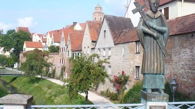 A statue of a historical figure, traditional buildings, and a stone wall.