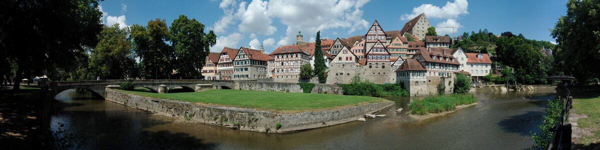 Eine historische Stadt mit einem Fluss, einer Steinbrücke und traditionellen Fachwerkhäusern.