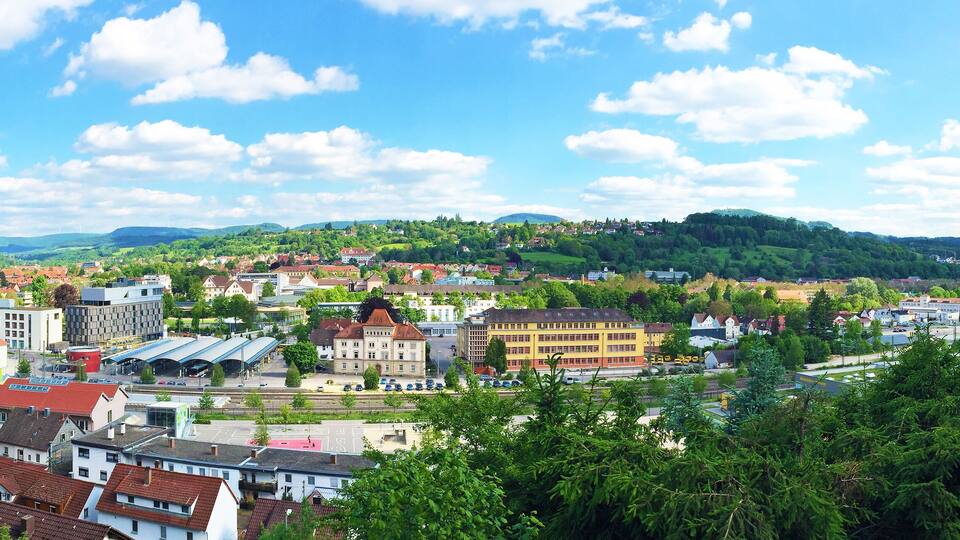 A town with a train station, buildings, and a hill in the background.