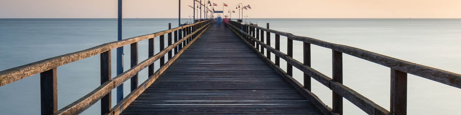 A wooden pier extending into calm waters under a clear sky.