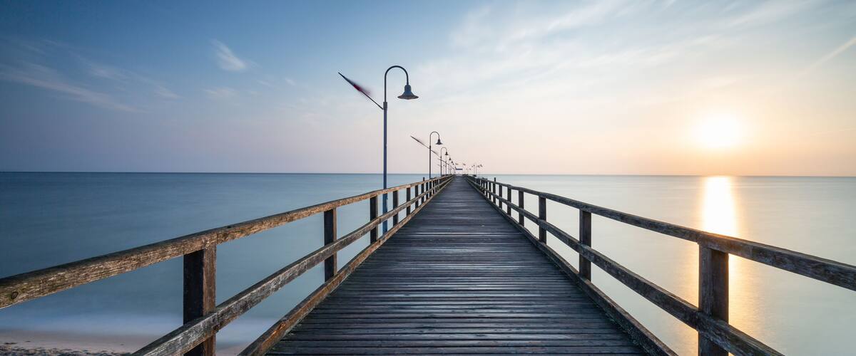 A wooden pier extending into calm waters at sunset.