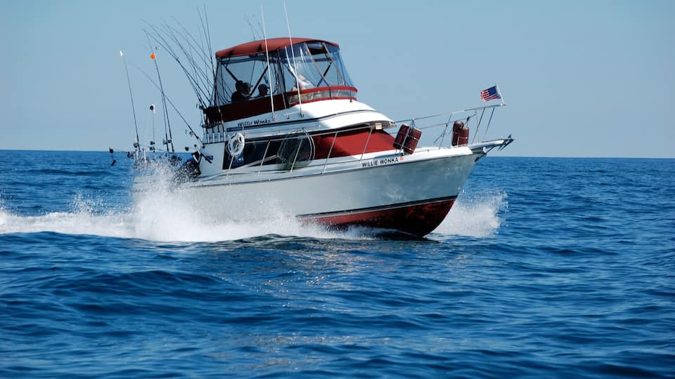 A red and white boat named Willie Wonka on the ocean.