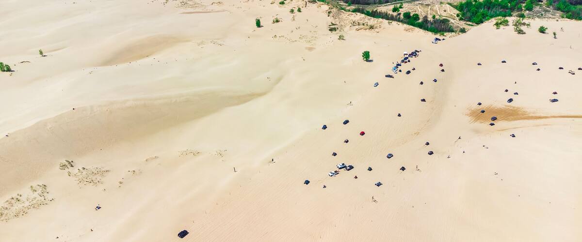 An aerial view of a desert landscape with scattered vehicles and sparse vegetation.