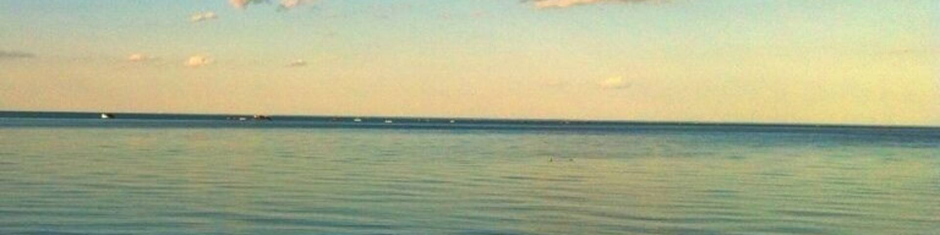 A calm sea with a clear sky and a few clouds.