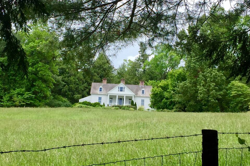 A white house surrounded by a field and trees.