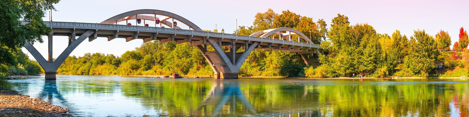 Rogue River Bridge, spanning Redwood Highway 25 in Grants Pass, Josephine County, Oregon. The arching bridge reflected on Rougue River at sunset.