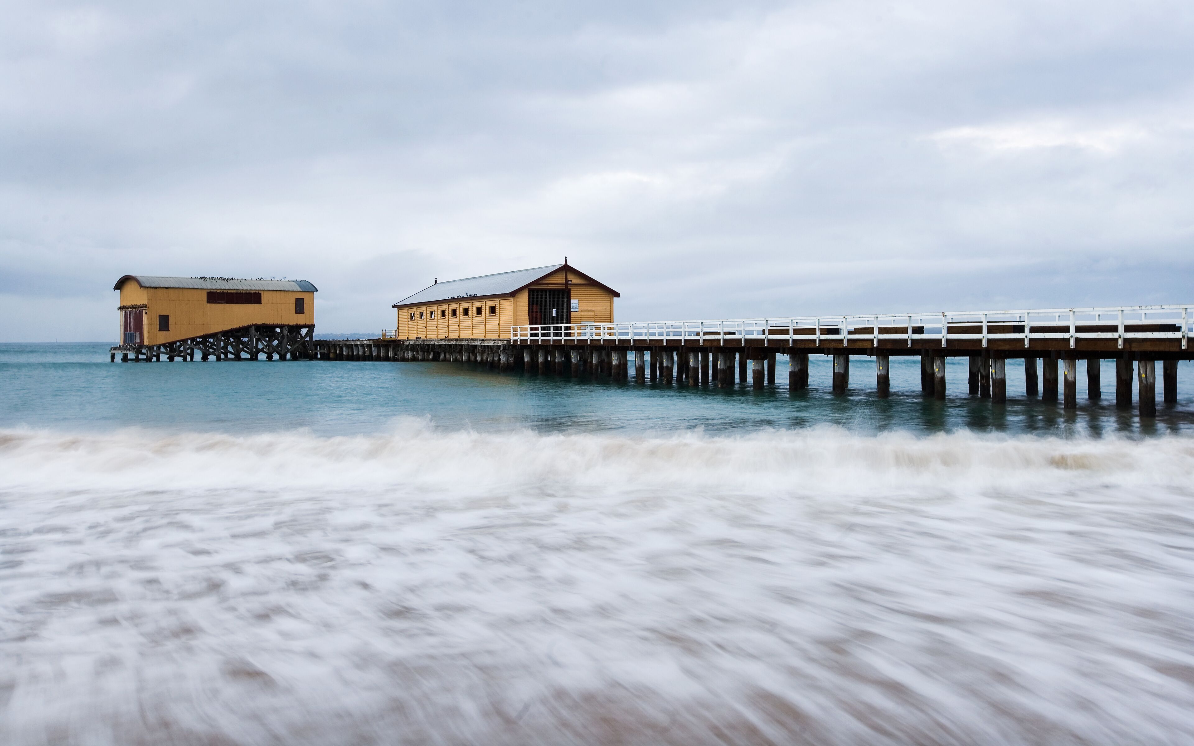 Panorama of long pier with boat sheds at end