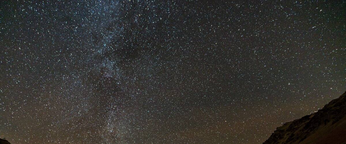 A starry night sky over a valley with a river.
