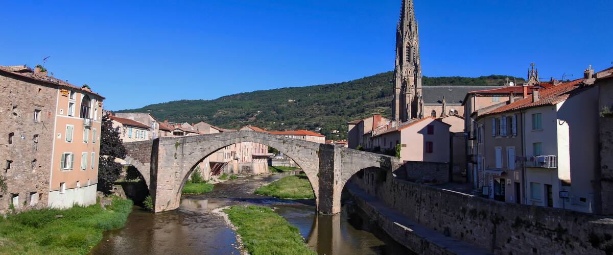 A stone bridge over a river, historic buildings, and a tall church spire.