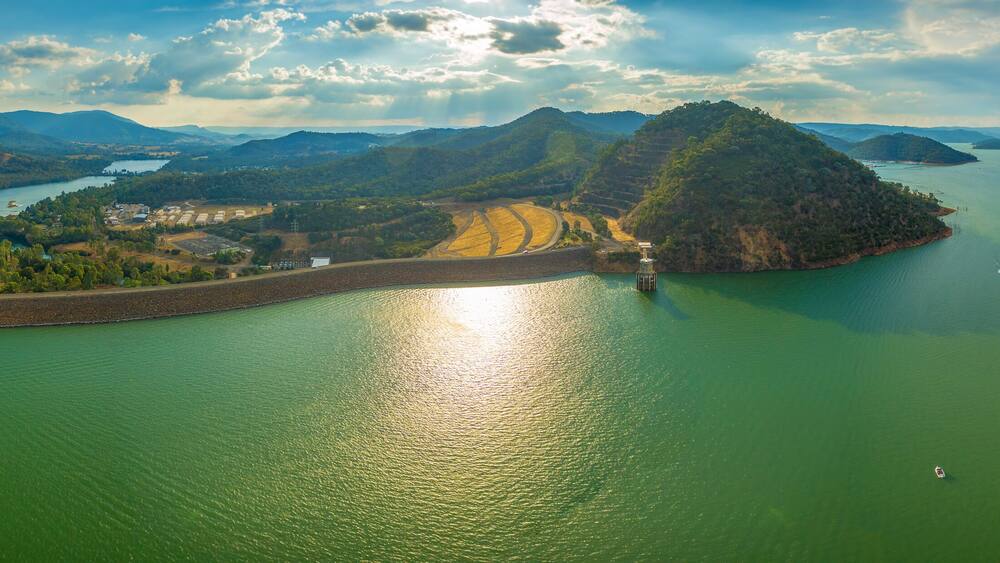 Une vaste étendue d’eau entourée de collines et d’une petite île, avec un barrage.