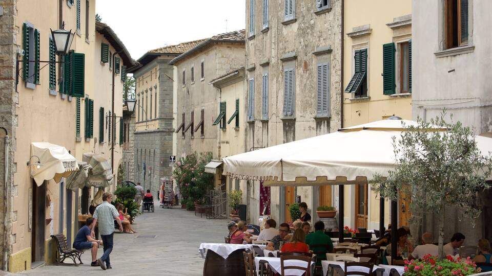A narrow street lined with buildings, outdoor seating at cafes, and people walking.