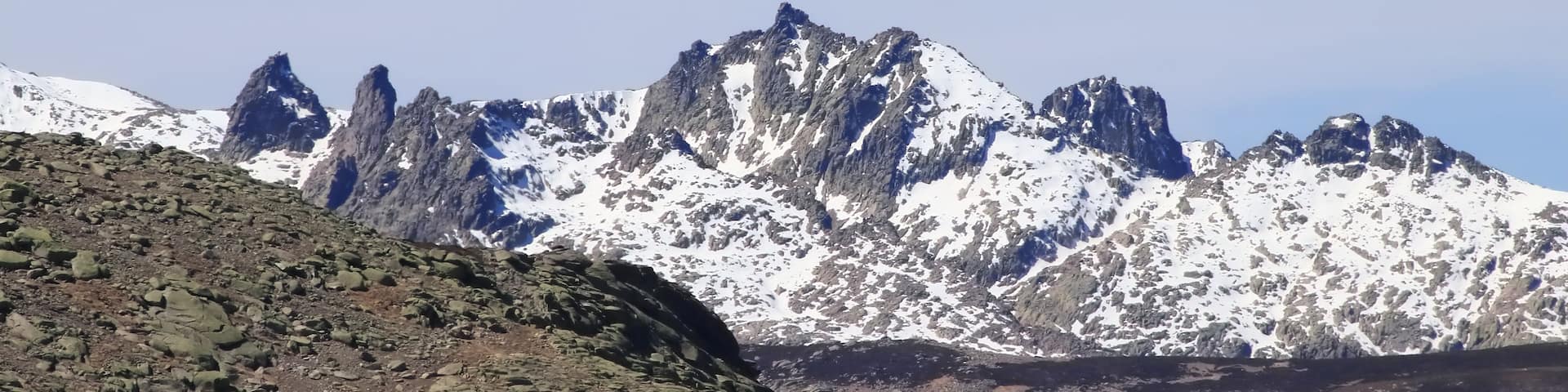 A mountain range with snow-capped peaks and rocky terrain.