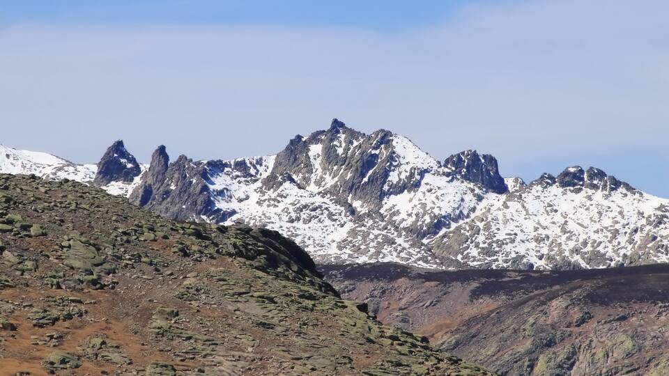 A mountain range with snow-capped peaks and rocky terrain.