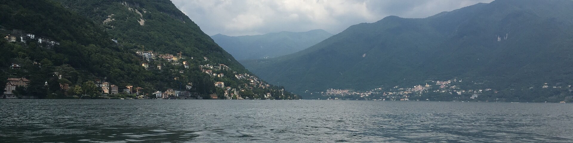 A lake with mountains in the background and a town on the left side.