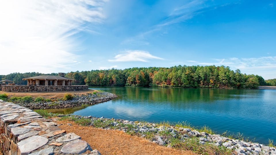 A lakeside view with a stone structure, a stone wall, and a forested island.