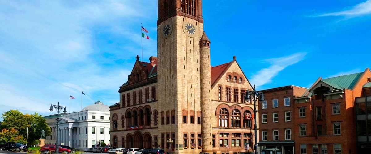 A historic building with a clock tower, surrounded by other buildings and a clear blue sky.
