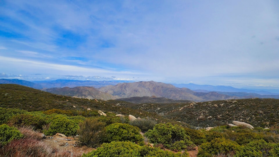A mountainous landscape with dense green vegetation and rocky outcrops.