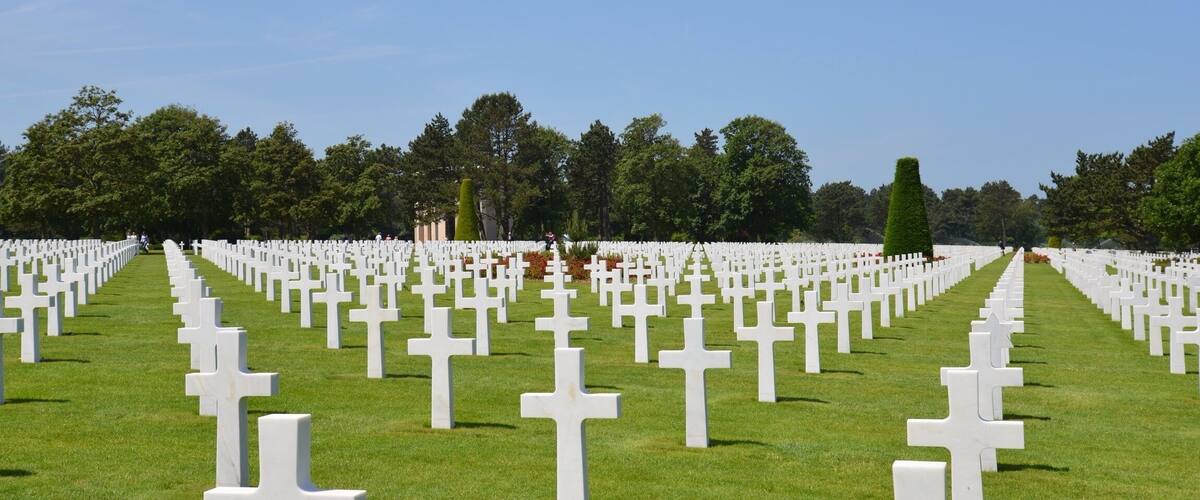 A cemetery with rows of white crosses on green grass.