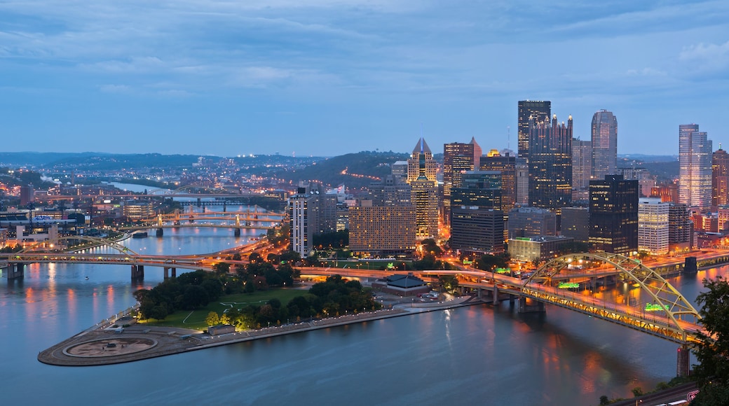 A city skyline at dusk with illuminated buildings and a river.