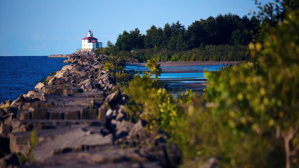 A lighthouse on a rocky shoreline with a clear blue sky.