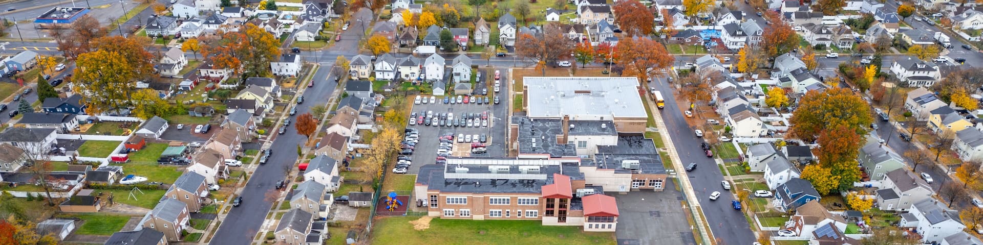Aerial view of Rahway NJ near East Milton showing homes, winding streets, waterways, the Rahway River and nearby roads like Route 1 and Route 27 under an overcast sky. Scenic suburban landscape.