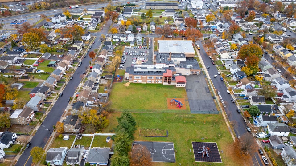 An aerial view of a residential neighborhood with houses, a school, and a basketball court.