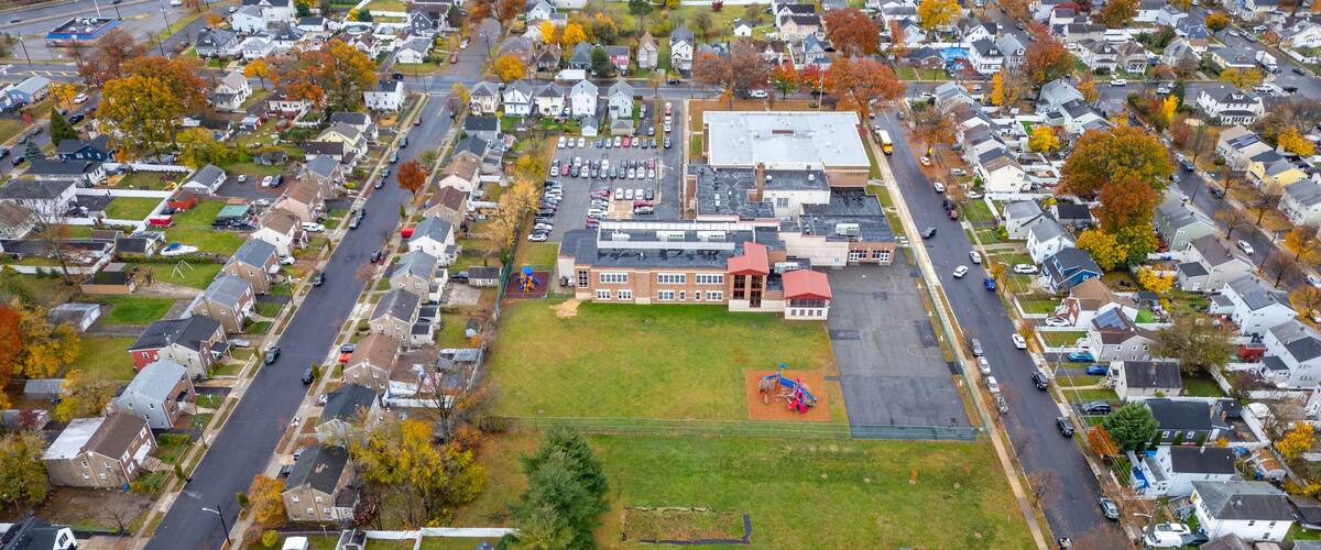 An aerial view of a residential neighborhood with houses, a school, and a basketball court.