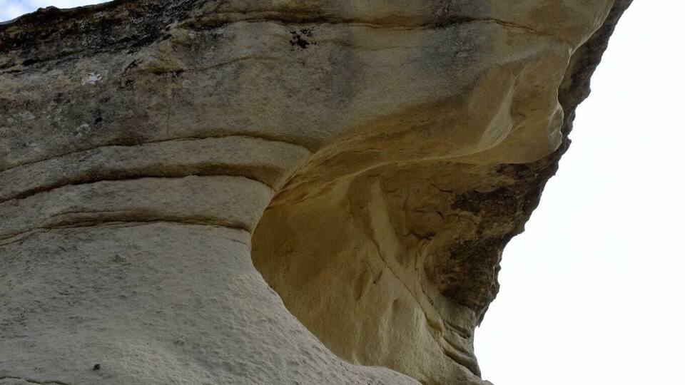 A large rock formation with a distinct overhang.