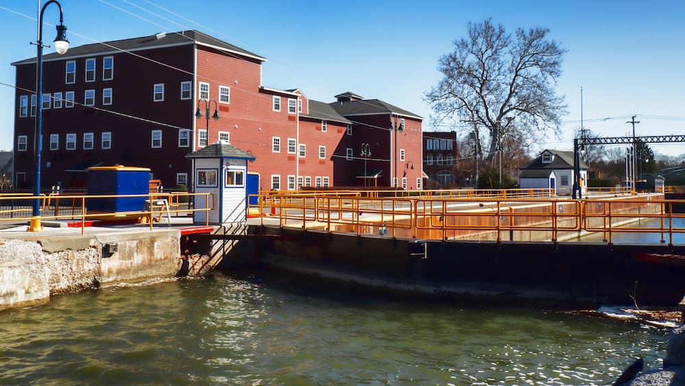 A lock system with a bridge, a red building, and a clear blue sky.