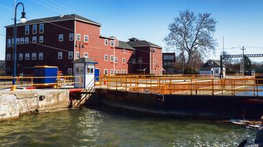 A lock system with a bridge, a red building, and a clear blue sky.