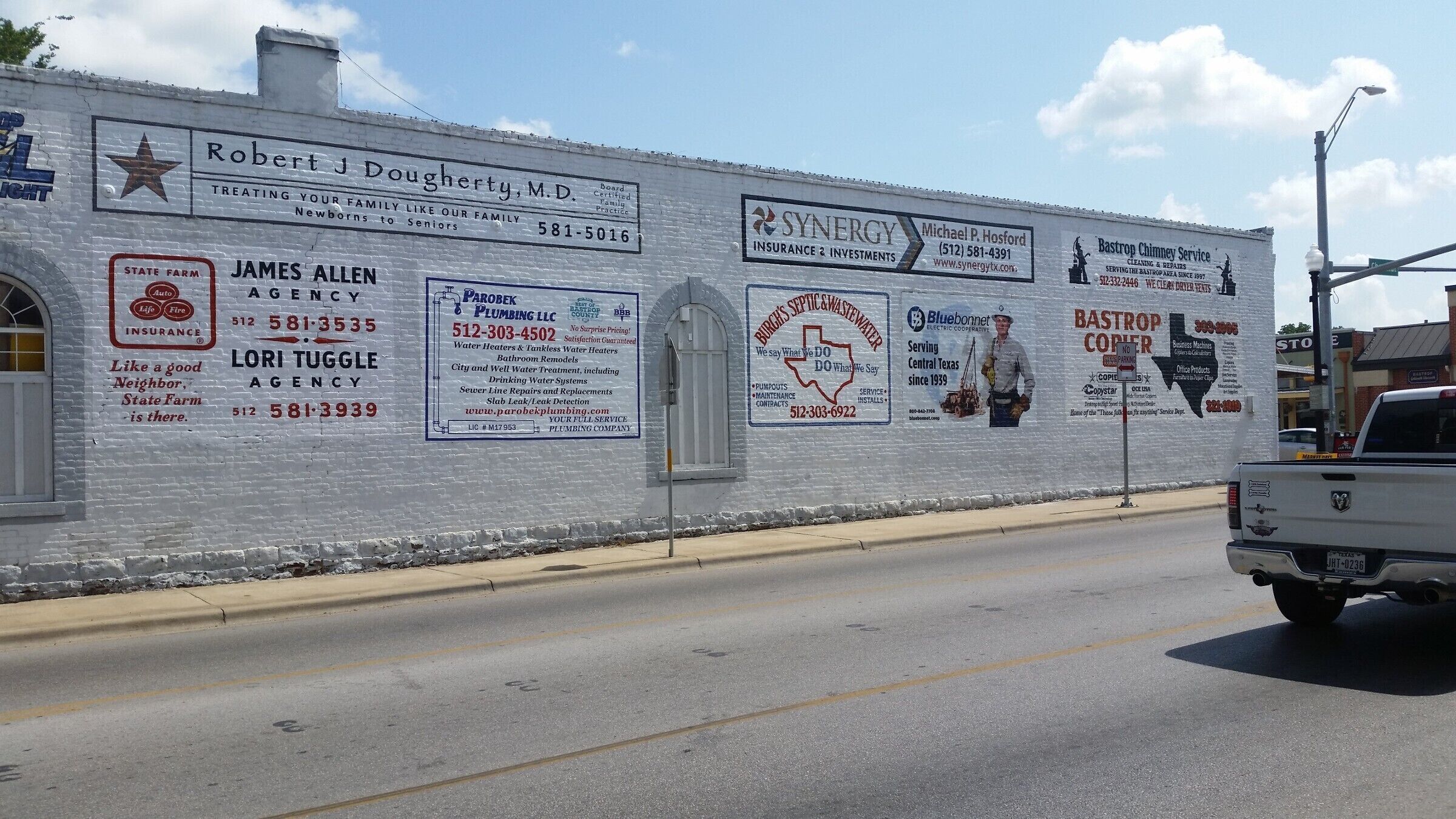 Signs painted on the side of a building at the corner of Chestnut and Main streets, Bastrop, Texas.