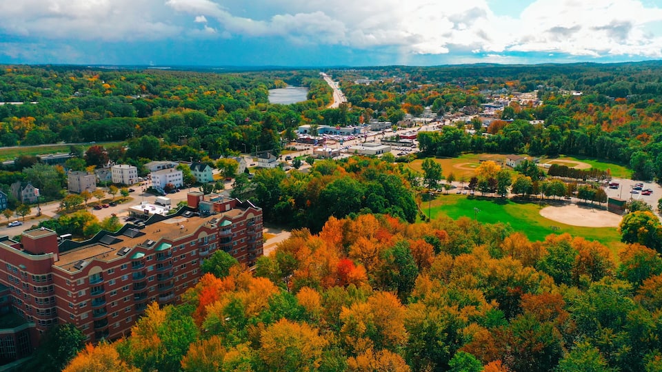 An aerial view of a town with autumn foliage, a river, and a baseball field.