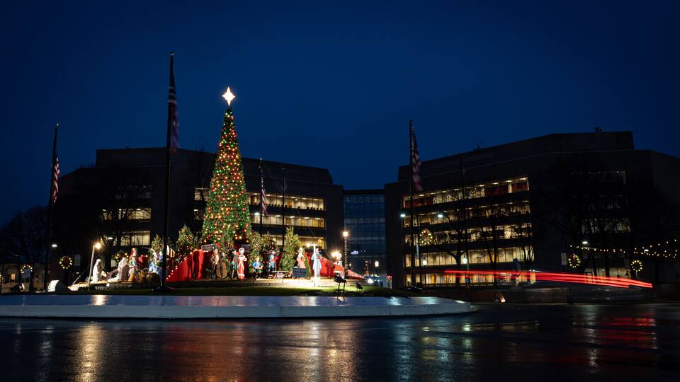 A Christmas tree with a star on top, surrounded by people and buildings.