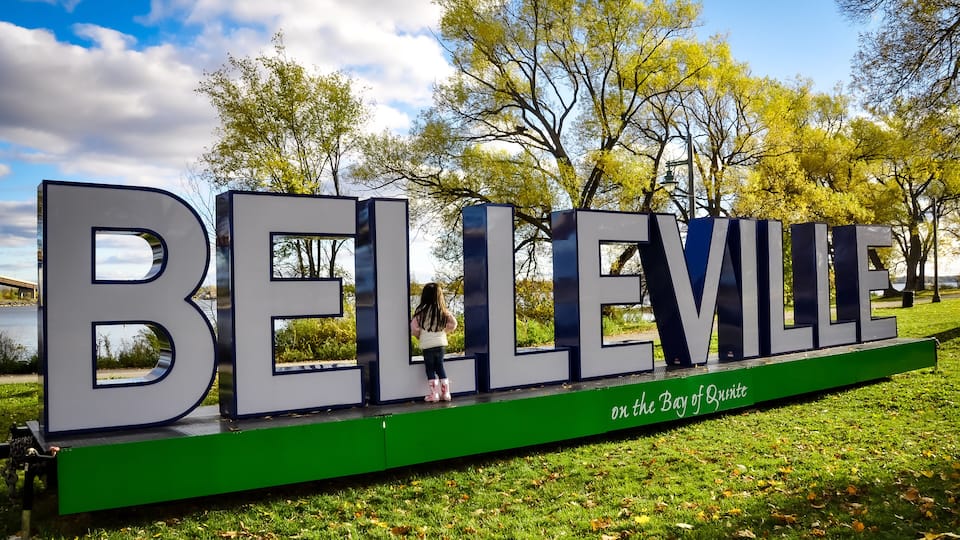 A large sign spelling 'BELLEVILLE' with a green base and the phrase 'on the Bay of Quinney' underneath.