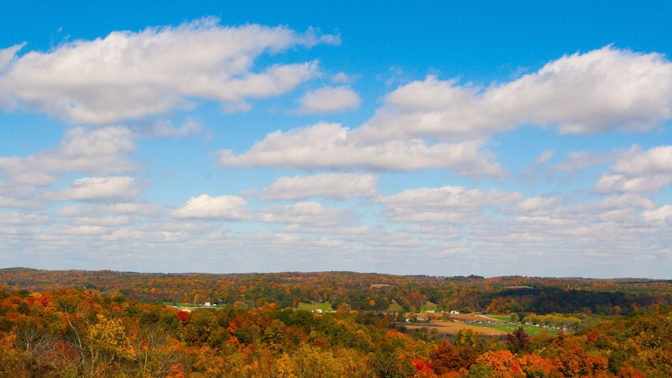 A landscape with autumn foliage, rolling hills, and a clear blue sky.
