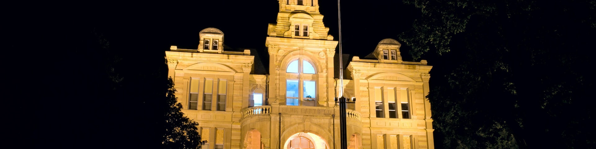 A large, illuminated building with a clock tower and arched windows at night.
