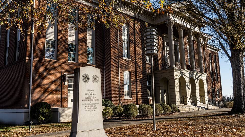 A brick building with columns and a plaque.
