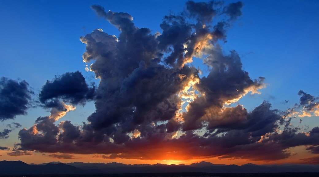 a panoramic shot of a colorful sunset over the front range of the colorado rocky mountains as seen form broomfield, colorado