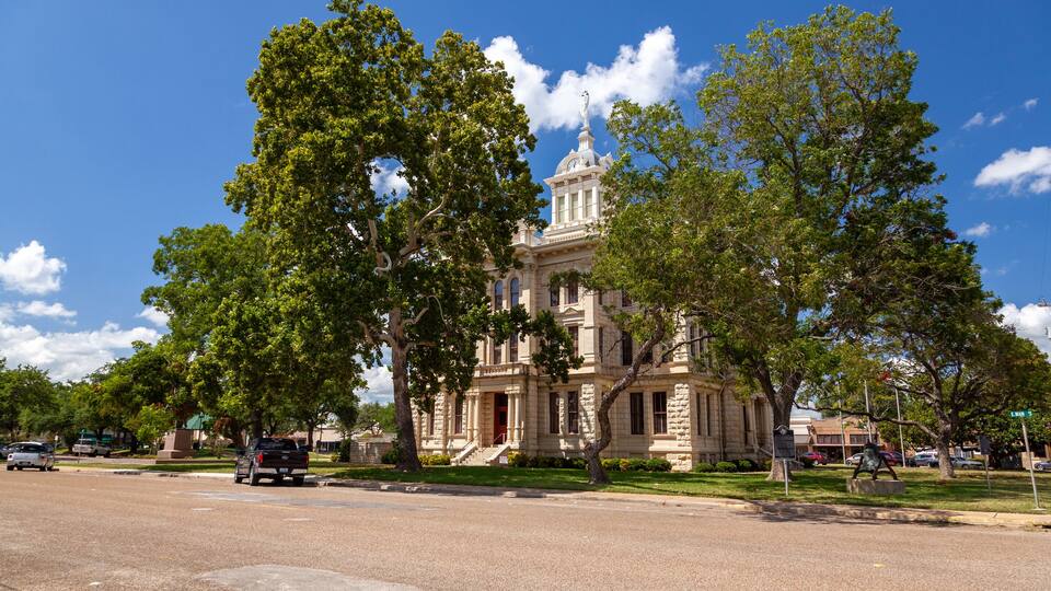 A historic building with a dome and columns, surrounded by trees and a clear blue sky.