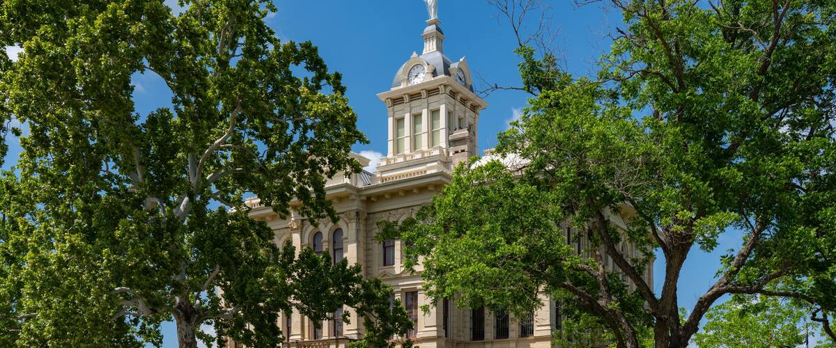 A historic building with a clock tower, surrounded by lush green trees.