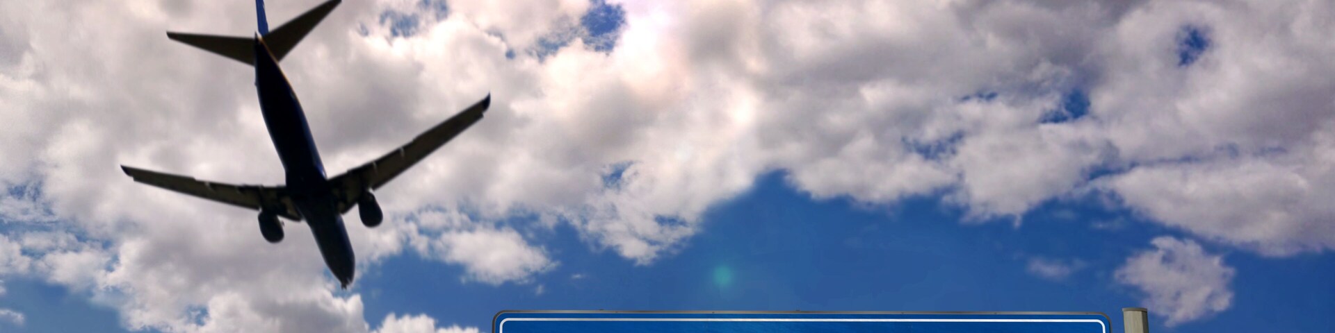 An airplane flying against a partly cloudy sky with a sign for Paris International Airport.