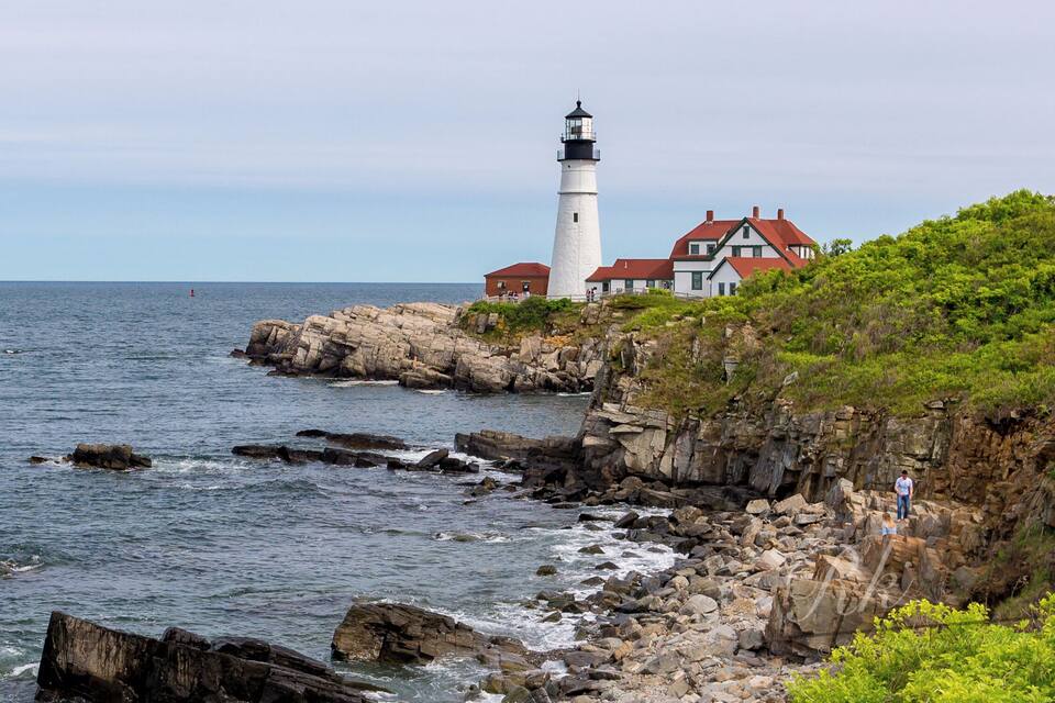 Un faro y una casa junto a la costa rocosa.