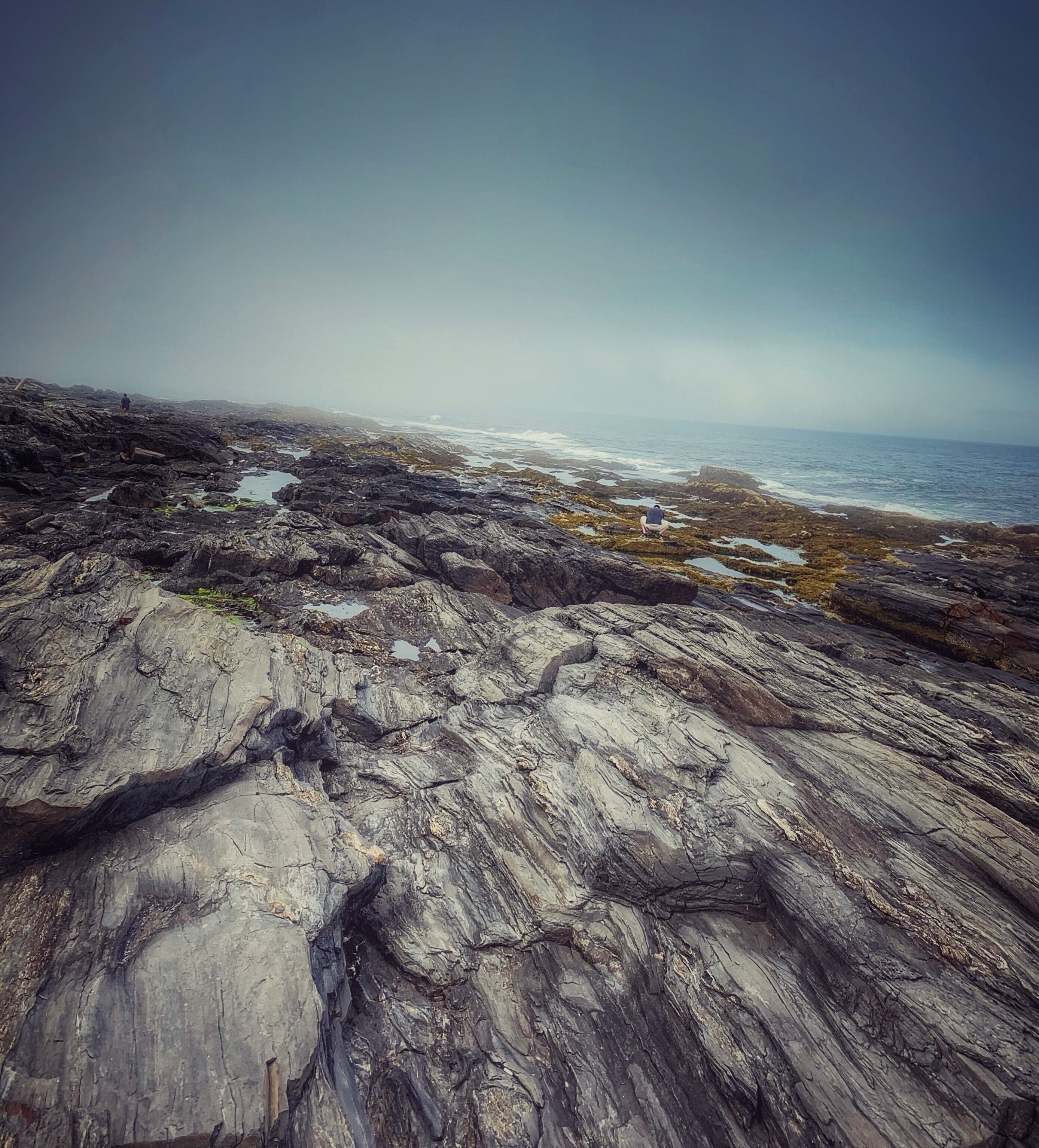 A rocky coastal landscape with waves crashing against the shore.