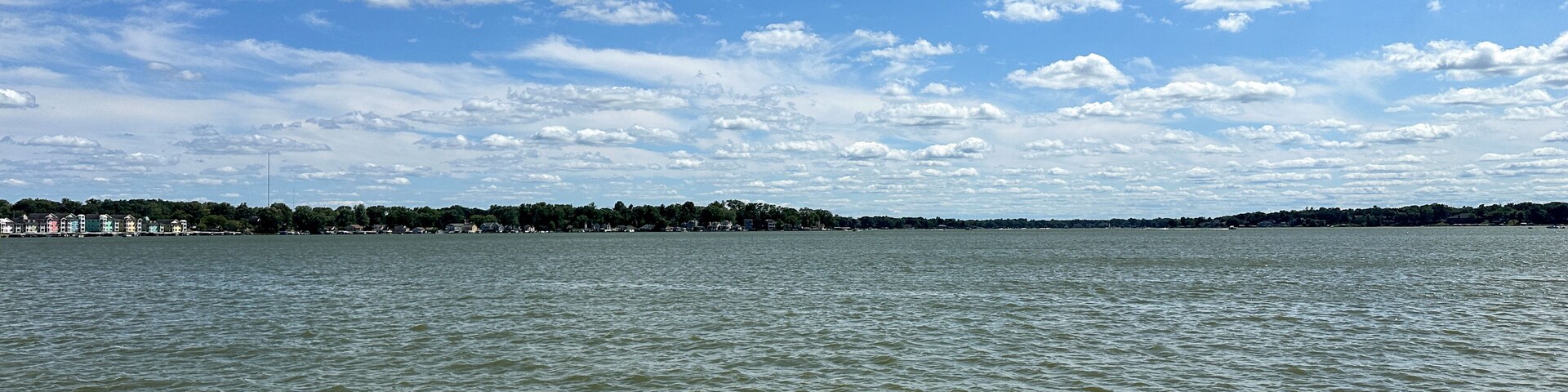 Un lago tranquilo con cielo despejado y algunas nubes dispersas.