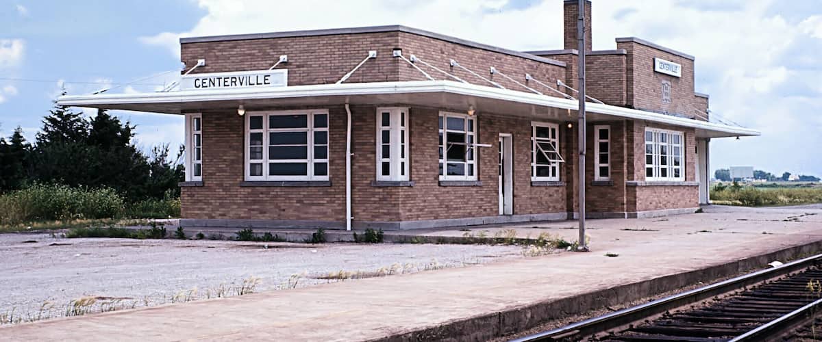 A brick train station named CENTERVILLE with a covered platform and tracks.