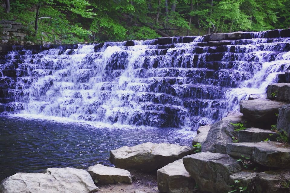 A multi-tiered waterfall surrounded by lush greenery.