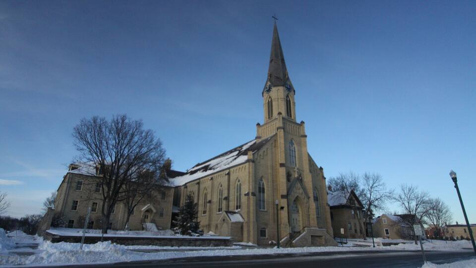 A church with a tall steeple and snow-covered surroundings.