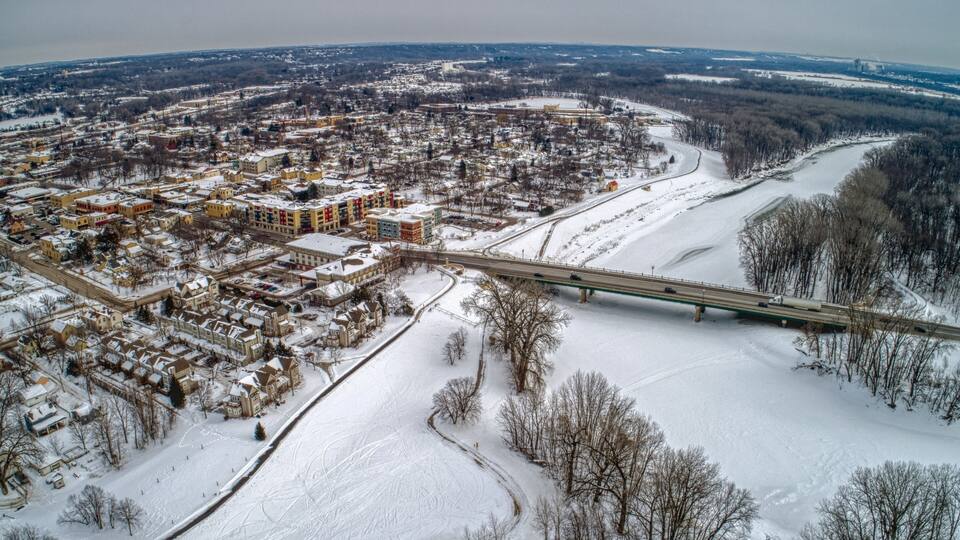 A snow-covered cityscape with a bridge crossing a river.